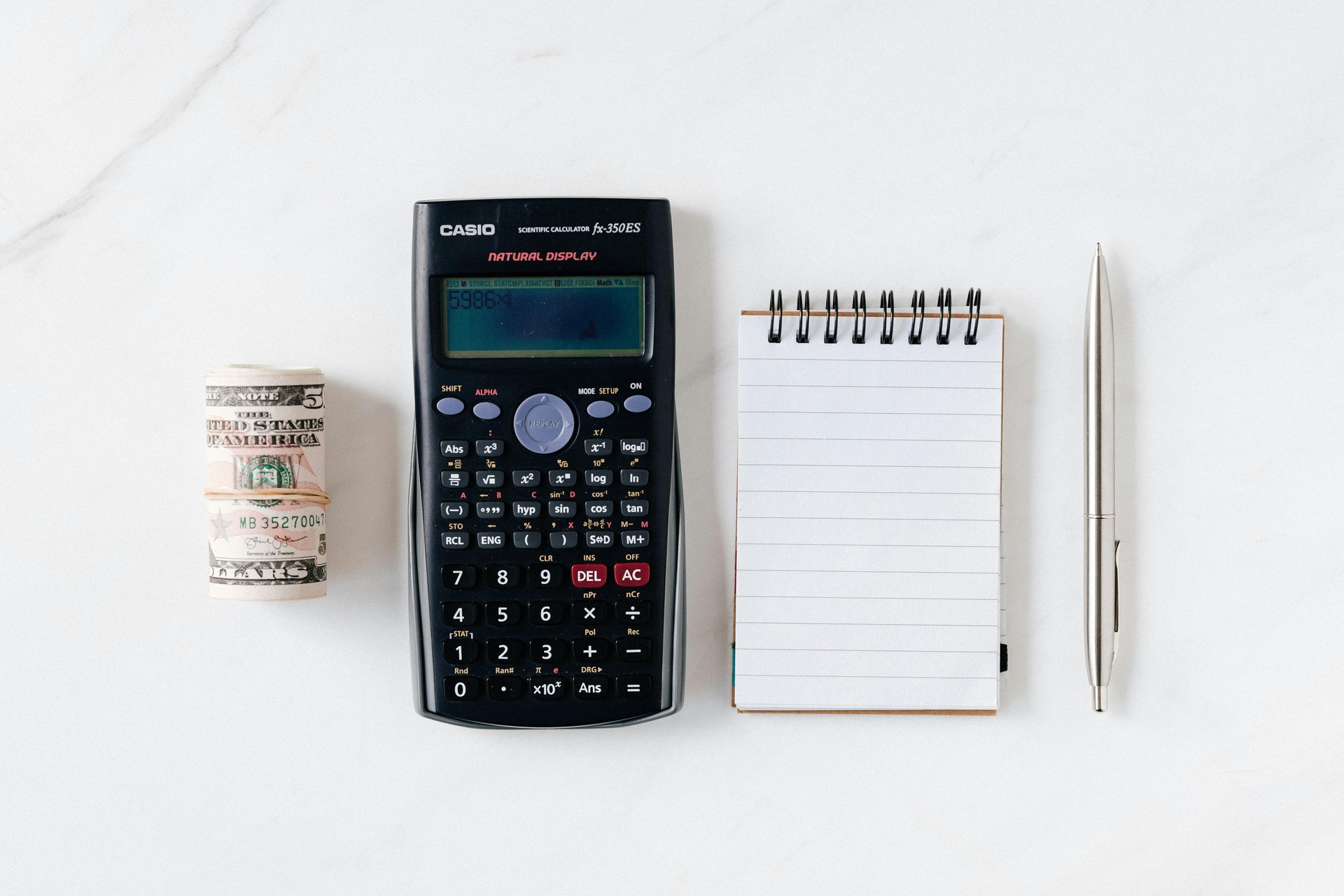 A-roll-of-a-cash-a-calculator-a-notebook-and-a-pen